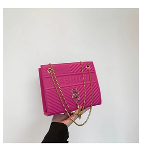 Détail macro du sac bandoulière fuchsia en similicuir avec chaîne dorée et logo SS