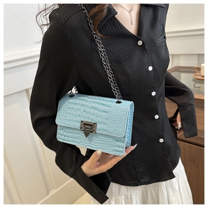 Detail of light blue croc-effect crossbody bag with gunmetal chain and triangle lock