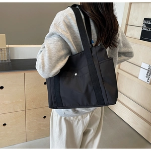 Dettaglio di una borsa tote nera con tasca laterale e fibbia in metallo per l'uso quotidiano