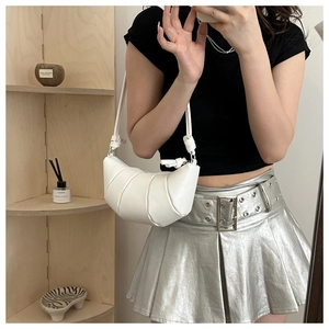 Detail of white pleated crescent bag with leather texture and minimalist metal finish