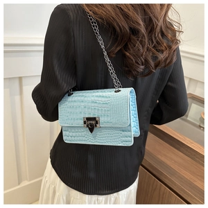 Close-up of light blue crocodile pattern texture and silver chain strap on crossbody bag