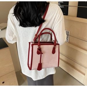 Gros plan du mannequin portant un sac cabas rose avec poignées rouges et bandoulière