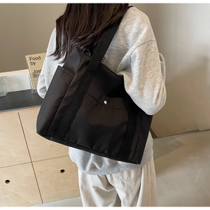 Modella che indossa una grande borsa tote nera in tela con tasca in una stanza