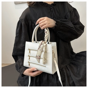 Close-up of white leather tote featuring metallic zippers and silk scarf handle detail
