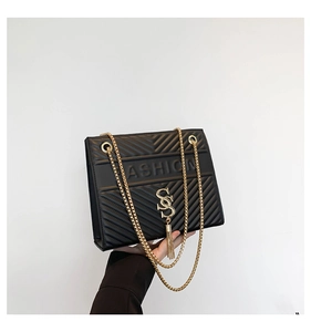 Détail du sac bandoulière noir matelassé en V avec chaîne dorée et pompon décoratif