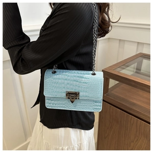 Detail of light blue faux crocodile skin texture and gunmetal rotary lock on handbag