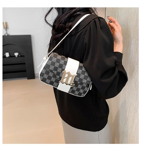Dettaglio borsa a spalla monogram con chiusura a lettera dorata e tracolla bianca