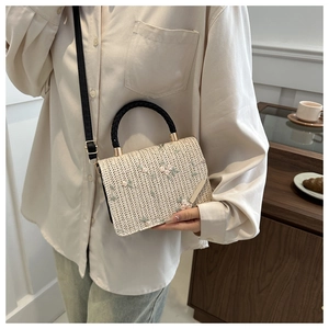 Détail du sac en paille avec broderie florale et poignée noire pour femme élégante