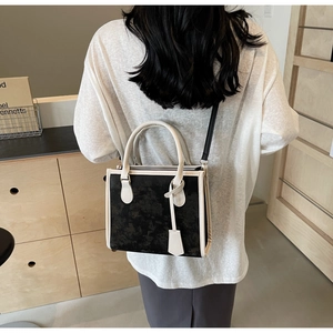 Détail du sac cabas contrasté porté, montrant la structure minimaliste en cuir noir et beige