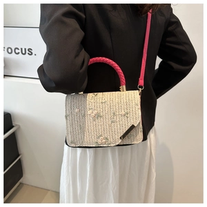 Détail de la broderie florale sur un sac tissé beige avec poignée magenta vif