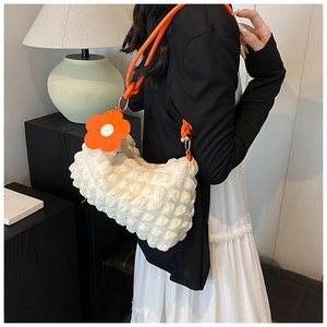 Detail of white bubble textured shoulder bag with orange strap and flower charm