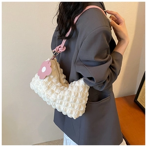 Detail of white quilted bubble bag with pink knotted strap and floral charm accessory