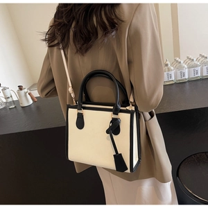 Mannequin portant un sac cabas beige et noir minimaliste dans un café élégant