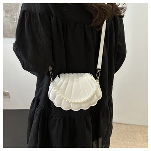 Dettaglio di una borsa bianca a forma di conchiglia con catena di perle e finta pelle