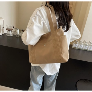 Dettaglio borsa tote kaki con ampia tracolla e tasca laterale in un ambiente caffè