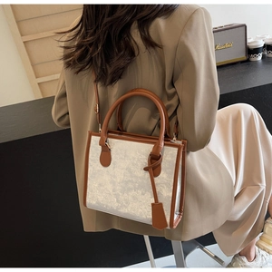 Détail d'un grand sac cabas argenté pailleté avec poignées en cuir marron et bandoulière longue