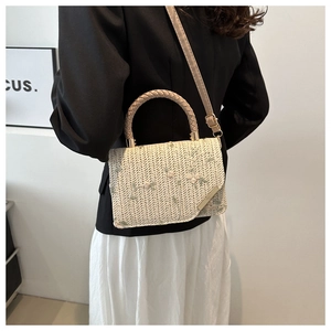 Détail du sac en paille beige avec broderie florale et bordure en métal doré
