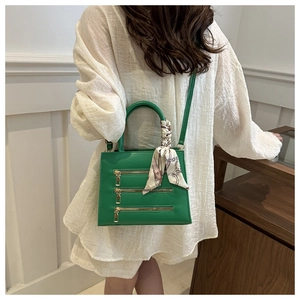 Detail of bright green leather tote with gold zippers and decorative silk scarf handle