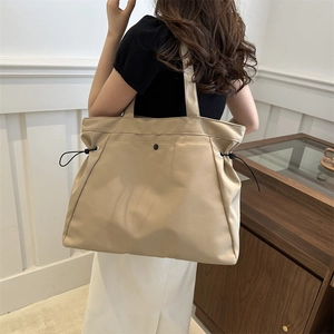 Minimalist beige oversized tote bag with drawstring side detail and wide shoulder strap