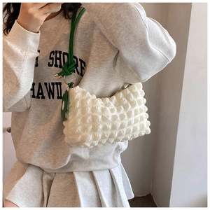 Close-up of white popcorn texture tote bag with bright green strap and metal ring detail