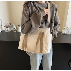 Dettaglio della grande borsa tote beige con ampie tracolle kaki e tasche esterne