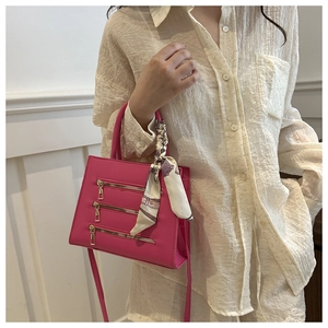 Detail of rose pink handbag with three gold zippers and floral scarf wrapped on handle