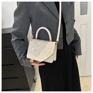 Détail du sac bandoulière tissé avec broderies florales et poignée ronde blanche