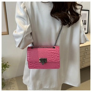 Detail of pink croc-embossed shoulder bag with black metal chain on a white blazer