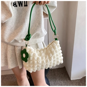 White bubble textured tote bag with green rope strap and floral pendant on shoulder