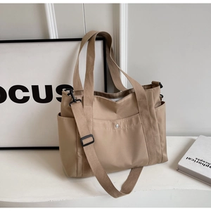 Dettaglio borsa tote in tela kaki con tracolla regolabile e tasche laterali funzionali