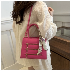 Pink leather handbag detail featuring decorative gold zippers and floral scarf handle wrap