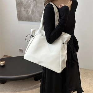 Minimalist white leather drawstring tote bag with wide shoulder strap for women