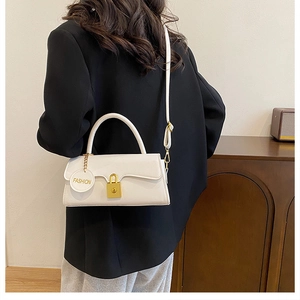 Detail of white leather underarm bag with gold lock and fashion tag on black coat