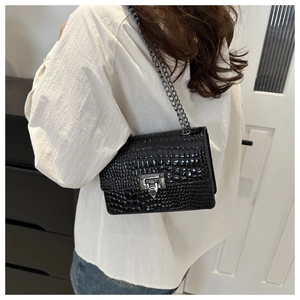 Detail of black crocodile pattern shoulder bag with silver clasp and metal chain strap