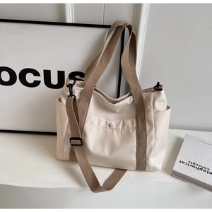 Dettaglio della borsa tote in tela beige con tracolla regolabile e tasche laterali capienti