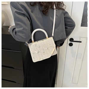 Détail d'un sac en paille tissé main avec broderie florale et bandoulière en cuir