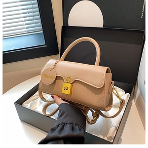 Detail shot of beige leather shoulder bag with gold padlock and fashion charm in gift box