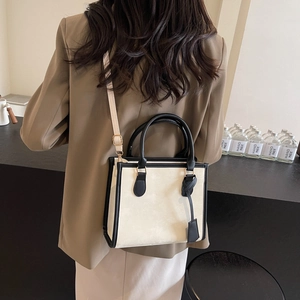 Sac fourre-tout crème minimaliste avec bordure noire et bandoulière porté par un modèle