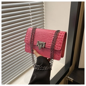 Detail of hot pink crocodile texture small square bag with metallic chain and buckle