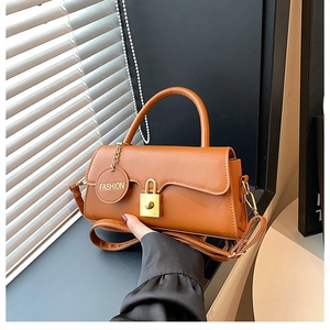Detail of a brown leather shoulder bag featuring a gold metal buckle and a fashion tag
