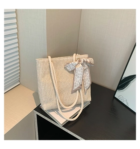 Detail of herringbone weave straw tote bag with knotted rope handles and heart print scarf