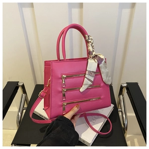 Detail of rose pink crossbody bag with decorative gold zippers and floral silk scarf