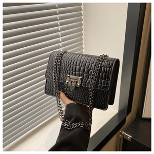 Detail of black faux crocodile leather small square bag with silver metal push-lock closure