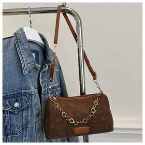 Detail der braunen Cord-Tasche mit Erdbeerprint und goldener Blumen-Zierkette für Damen