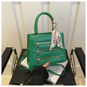 Close-up of bright green PU leather tote with metal zippers and geometric silk scarf handle