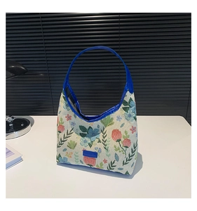 Detail of floral jacquard tote bag with blue leather handles and vibrant pink flower pattern