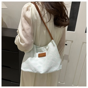 Detail of mint green woven hobo bag showing brown leather strap and textured surface