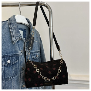 Detail der schwarzen Cord-Schultertasche mit Erdbeermuster und goldener Blumen-Kette