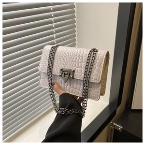 Detail of white crocodile embossed leather handbag with charcoal grey metal chain and buckle