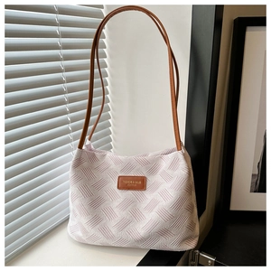 Detail of pink and white woven tote bag with brown leather straps and fashion label